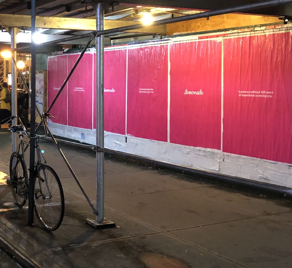 Lemonade pink wild postings along a sidewalk: Insurance made for the century you're in, and Insurance without 100 years of experience screwing you